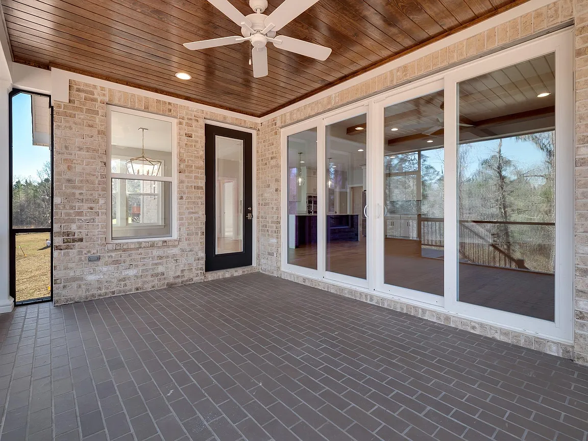 Screened porch with glass patio doors and brick flooring.